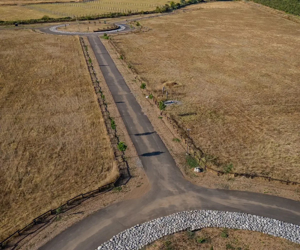 Camino interior asfaltado y rotonda con jardín de piedras, desde el aire