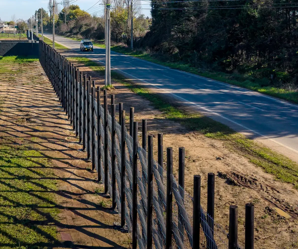 Cierre perimetral de postes de madera frente al camino público