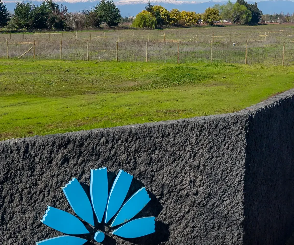 Isotipo azul en el muro de acceso, con la cordillera nevada al fondo